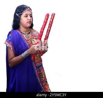 Donna tradizionale gujarati con bastoncini dandiya su sfondo bianco, durante le celebrazioni Navratri, donne indiane nella cultura tradizionale. focu selettiva Foto Stock