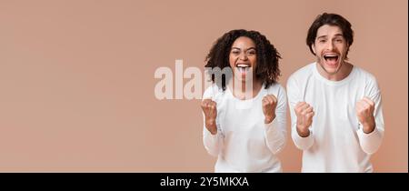 Felice coppia interrazziale che urla e stringe pugni con entusiasmo Foto Stock