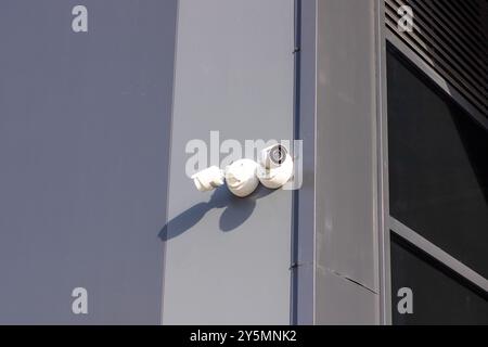 C'è una telecamera di sicurezza montata sul lato di un grande edificio che si affaccia sull'area per scopi di sorveglianza Foto Stock