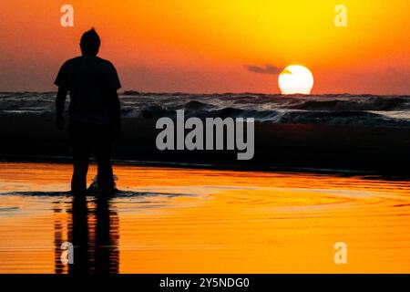 Isola di Palms, Stati Uniti. 22 settembre 2024. Una donna, sagomata dal sole, si ferma per vedere l'alba mentre sbircia sull'orizzonte dell'Oceano Atlantico, 22 settembre 2024 a Isle of Palms, Carolina del Sud. Crediti: Richard Ellis/Richard Ellis/Alamy Live News Foto Stock