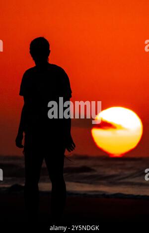 Isola di Palms, Stati Uniti. 22 settembre 2024. Una donna, sagomata dal sole, si ferma per vedere l'alba mentre sbircia sull'orizzonte dell'Oceano Atlantico, 22 settembre 2024 a Isle of Palms, Carolina del Sud. Crediti: Richard Ellis/Richard Ellis/Alamy Live News Foto Stock