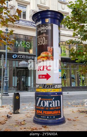 Colonna pubblicitaria Morris Column in via Váci fuori da Duna Plaza, Budapest Ungheria, ristorante ungherese McDonalds pubblicitario Foto Stock