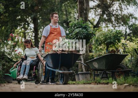 Ragazzo con sindrome di Down e ragazza in carrozzina giardinaggio insieme Foto Stock