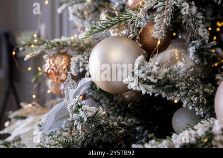 Elegante albero di Natale con giocattoli bianchi e rosa e scatole regalo nella camera da letto degli appartamenti di lusso Foto Stock