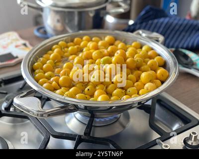 Piccole mele gialle in pentola su una stufa a gas. Dessert saporito, marmellata, preparazioni per l'inverno. Raccolto in giardino. Prodotto biologico. Foto Stock