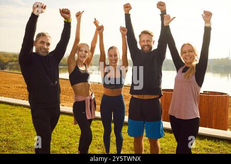 Persone felici e soddisfatte in piedi sulla riva del lago dopo gli esercizi sportivi nel parco. Foto Stock