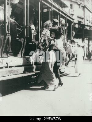 Foto d'epoca di tram che arrivano in auto a Broadway. STATI UNITI. 11 luglio 1913. Due donne, una che aiuta un bambino, salgono sul tram, New York City. Foto Stock