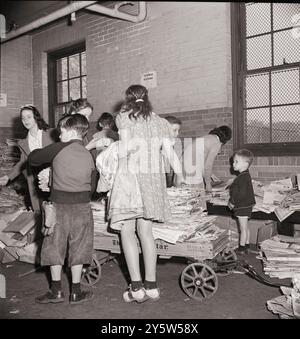 America degli anni '1940 Campagna di recupero rottami, programma Victory. I bambini delle scuole portano i loro rottami di carta dalle loro aule in cantina, dove viene prelevata da un camion dell'azienda cartaria. STATI UNITI. Washington, D.C. maggio 1942 di M. Collins, fotografo Foto Stock