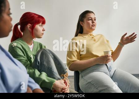 Gruppo di diversi colleghi seduti in un ufficio che discutono. Gli individui sono impegnati nella conversazione, nella condivisione di idee e nella collaborazione in un ambiente informale Foto Stock