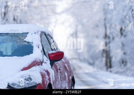 Auto su una strada invernale attraverso una foresta innevata. Foto Stock