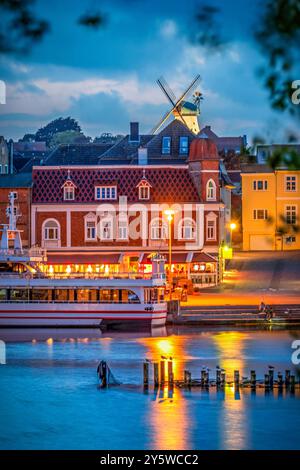 Vista di alcuni edifici sulla riva del fiume Schlei nella piccola città di Kappeln in Germania all'ora blu, verticale Foto Stock