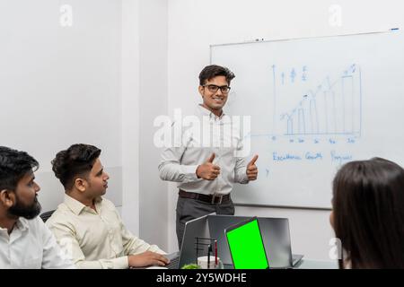 Questa immagine rappresenta una riunione dinamica del team aziendale in un ambiente elegante e moderno. La figura centrale, un giovane capo con gli occhi espressivi, è Foto Stock