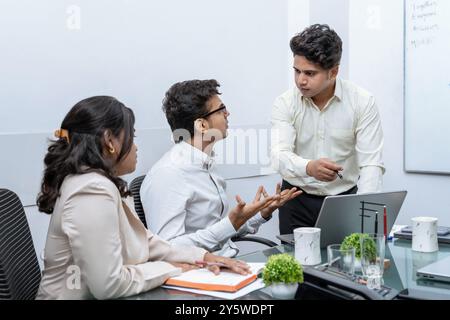 Riunione in sala riunioni riscaldata in cui diversi dipendenti, tra cui un uomo d'affari asiatico, sono impegnati in un'accesa discussione sui rapporti finanziari e sulle vendite. Foto Stock