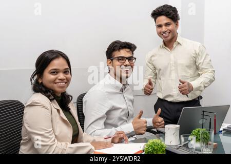 Un team aziendale diversificato e multirazziale di varie età celebra il successo di carriera in un ambiente di ufficio moderno. Il team è visibilmente entusiasta, mostrando il suo valore Foto Stock