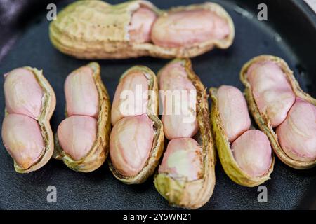 Primo piano di arachidi nella piastra nera Foto Stock