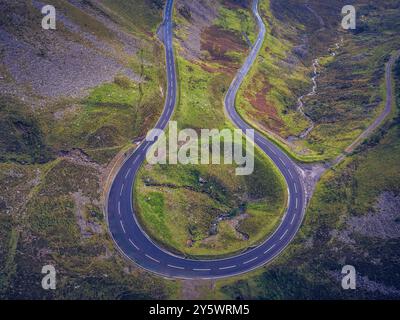 Una tortuosa strada di montagna curva attraverso lussureggianti colline verdi, creando un percorso suggestivo e panoramico. Foto Stock