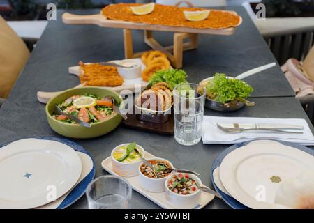 Un tavolo con vari piatti tra cui insalate, antipasti e una portata principale, pronti per un pasto in un ristorante. Foto Stock