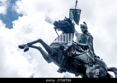 Una statua drammatica di un uomo su un cavallo che cresce contro un cielo nuvoloso, che mostra la grandezza storica. Foto Stock