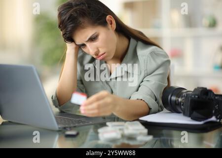 Fotografo triste che guarda la scheda di memoria dopo la perdita di dati a casa Foto Stock