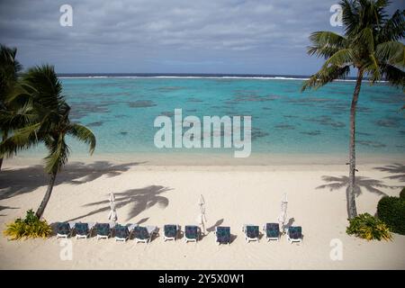 Spiaggia incontaminata con lettini sotto le palme che si affaccia su un mare turchese, Titikaveka, Rarotonga, Isole Cook Foto Stock