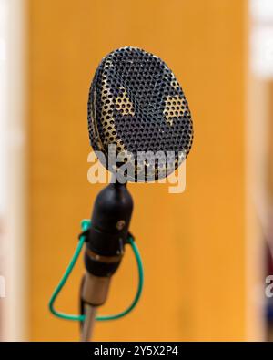 Microfono vintage su sfondo arancione sfocato su un supporto per microfono. Foto Stock