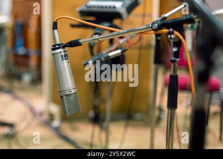 Microfono da studio con filtro pop su sfondo sfocato di apparecchiature musicali. Foto Stock