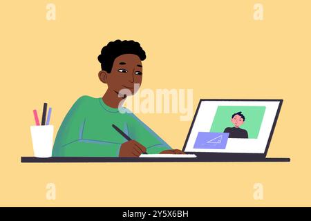 Un giovane adulto è impegnato in una videochiamata mentre prende appunti accanto a un portatile su una scrivania con cancelleria. Foto Stock