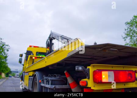 vista sul lato posteriore inferiore e retroilluminazione rossa di un veicolo di recupero giallo lungo il lato sinistro della carrozzeria e lungo la strada Foto Stock