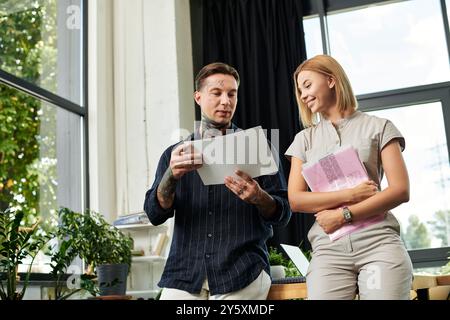 Due giovani professionisti condividono idee durante la revisione dei documenti in un ufficio moderno. Foto Stock