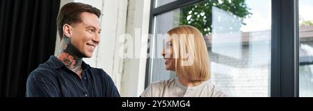 Due colleghi condividono un momento di allegria, favorendo il lavoro di squadra nel loro elegante spazio di lavoro. Foto Stock