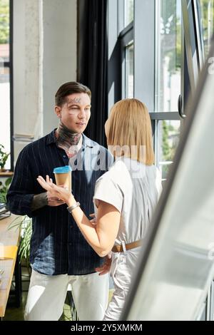 Due giovani professionisti condividono idee e risate mentre si gusta un caffè vicino alla finestra. Foto Stock