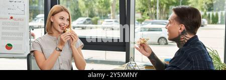 Due colleghi condividono un momento leggero mentre mangiano la pizza insieme al lavoro. Foto Stock