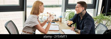 Due giovani colleghi condividono un momento di luce durante il pranzo, discutendo con calore i loro progetti e le loro idee. Foto Stock