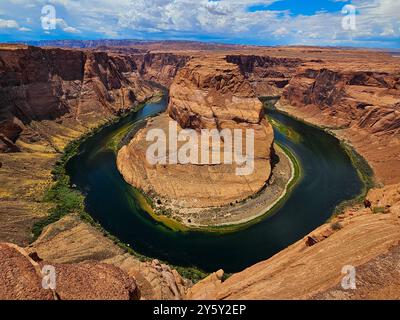 Una vista mozzafiato dell'Horseshoe Bend in Arizona con il fiume Colorado che si snoda intorno alla formazione rocciosa sotto un cielo azzurro. Foto Stock