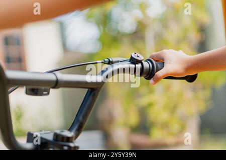 Un'immagine ravvicinata di una mano che afferra il manubrio di una bicicletta, che mostra l'avventura all'aperto e il ciclismo in un ambiente naturale. Foto Stock