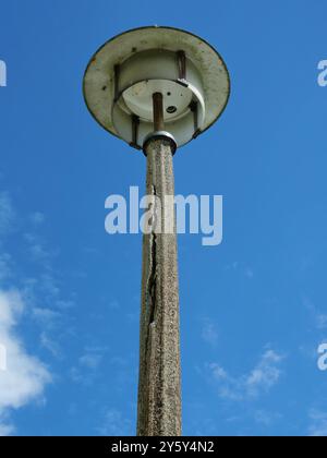 Una vecchia lampada da strada deteriorata di DDR Times. Il palo in cemento danneggiato e l'impianto di illuminazione usurato evidenziano la necessità di modernizzazione. Foto Stock