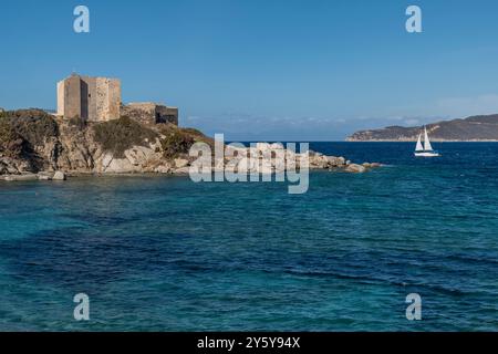 Una barca a vela bianca naviga nei pressi della Fortezza Vecchia a Villasimius, in Sardegna Foto Stock