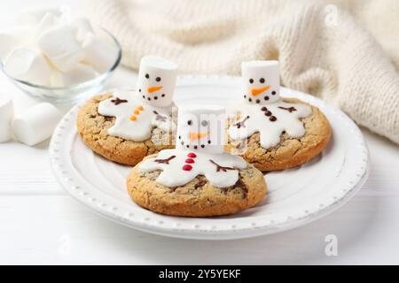 Deliziosi biscotti con pupazzi di neve fatti di marshmallow su tavola bianca, primo piano Foto Stock