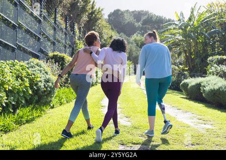 Camminando insieme, diverse donne e amiche si godono una passeggiata all'aperto nel lussureggiante giardino Foto Stock
