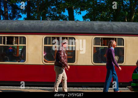 Holt, Norfolk, Regno Unito - 21 SETTEMBRE 2024: L'uomo vestito con giacca in pelle Airforce marrone anni '1940 e cappello cammina sulla piattaforma di fronte al vagone ferroviario Heritage Foto Stock