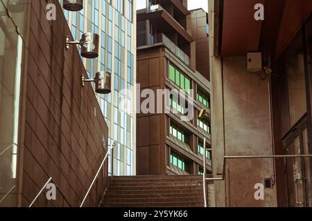 Scala urbana tra edifici contemporanei con eleganti facciate in vetro e finestre verdi, che mettono in risalto l'architettura moderna della città Foto Stock