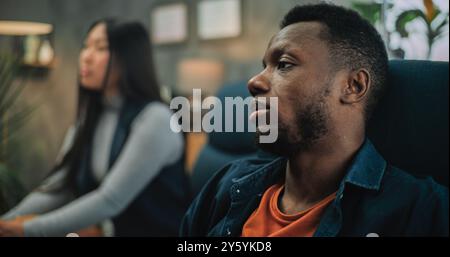 Primo piano di un uomo afroamericano e di una giovane donna asiatica che discutono di problemi, parlando di conflitti di relazione durante la terapia di coppia. Famiglia giovanile multietnica su consultazione con psicoterapeuta. Foto Stock