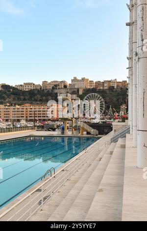 La piscina dello Stadio Nautico Rainier III si affaccia su Port Hercule, con la Rocca di Monaco sullo sfondo al tramonto, Monte Carlo Foto Stock