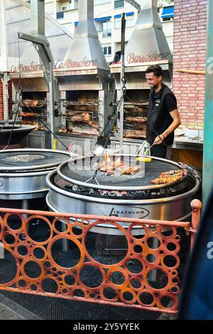 Un giovane cuoco grigliando spiedini di carne e pannocchie di mais al mercatino di Natale di Port Hercule, durante le vacanze invernali, Monte Carlo, Monaco Foto Stock