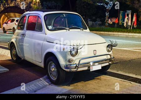 Parcheggiata Fiat 500 auto d'epoca decorata con false ciglia applicate ai fari, in una strada della città di Monaco di notte, Principato di Monaco Foto Stock