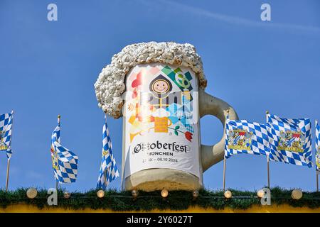 Monaco di Baviera, Germania - 23 settembre 2024: La tazza di birra gigante con il motivo ufficiale dell'Oktoberfest 2024 e il Münchner Kindl simboleggia l'ospitalità e la gioia di vivere del Wiesn *** Der riesige Bierkrug mit dem offiziellen Oktoberfest-Motiv 2024 und dem Münchner Kindl symbolisiert die Gastfreundschaft und Lebensfreude der Wiesn Foto Stock