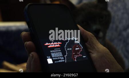 Una persona anziana possiede uno smartphone con un messaggio inviato dall'IDF ai residenti nel sud del Libano e a Beqaa, avvertendoli di stare lontano dagli edifici utilizzati da Hezbollah per immagazzinare armi, dopo che l'esercito israeliano ha promesso di effettuare attacchi più estesi e precisi contro Hezbollah il 22 settembre 2024 Foto Stock