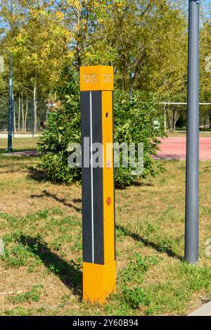 Citofono giallo nel parco per la comunicazione di emergenza su un palo con l'iscrizione SOS. Entra nel parco. Foto Stock