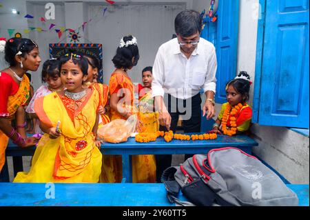 La Nabin Nagar Primary School è una remota scuola rurale situata a Nabin Nagar, lungo il confine tra India e Bangladesh. Nonostante le sfide, la scuola celebra il giorno degli insegnanti il 5 settembre, in occasione del compleanno del Dr. Sarvepalli Radhakrishnan, secondo presidente dell'India. Il preside della scuola prende l'iniziativa di organizzare la celebrazione, preparando ghirlande di fiori di calendula per le sue studentesse prima della loro esibizione di danza. Nabin Nagar, Bengala Occidentale, India. Foto Stock