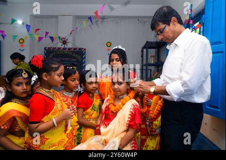 La Nabin Nagar Primary School è una remota scuola rurale situata a Nabin Nagar, lungo il confine tra India e Bangladesh. Nonostante le sfide, la scuola celebra il giorno degli insegnanti il 5 settembre, in occasione del compleanno del Dr. Sarvepalli Radhakrishnan, secondo presidente dell'India. Il preside della scuola prende l'iniziativa di organizzare la celebrazione, preparando ghirlande di fiori di calendula per le sue studentesse prima della loro esibizione di danza. Nabin Nagar, Bengala Occidentale, India. Foto Stock